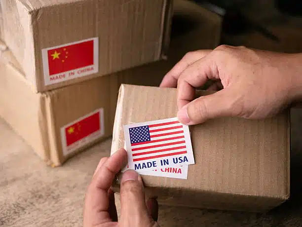 Person placing a “Made in USA” sticker over a “Made in China” box