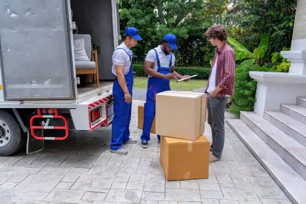 Movers delivering and verifying packages in front of a residential house
