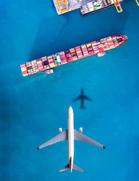 Airplane flying over a cargo ship transporting containers