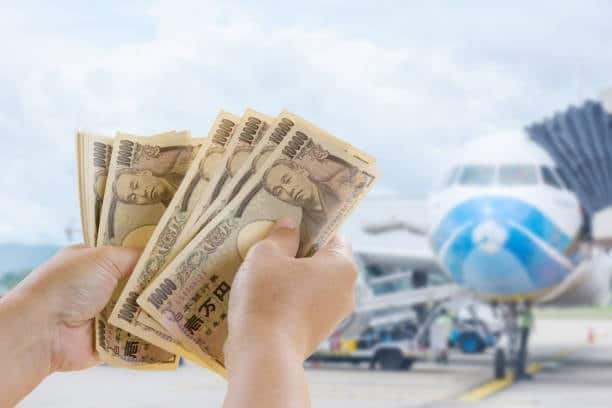 Japanese yen in hand with airplane in background representing air freight costs