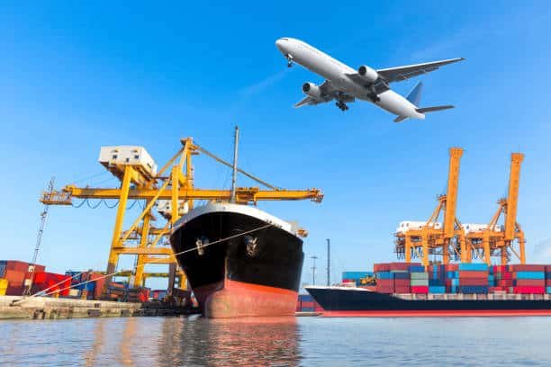 Large cargo ship docked at Turkish port with an airplane flying overhead – illustrating air and sea freight from China to Turkey.