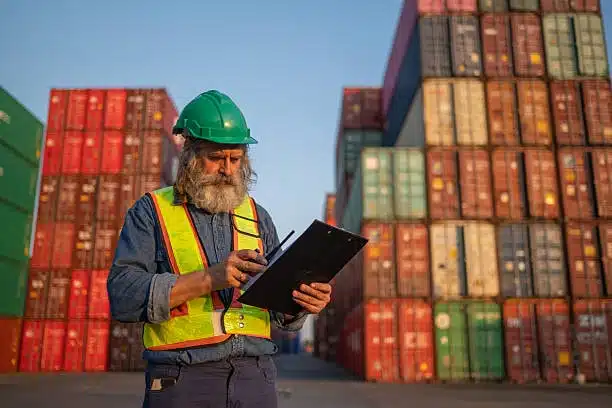 Freight manager inspecting shipping containers and reviewing export paperwork