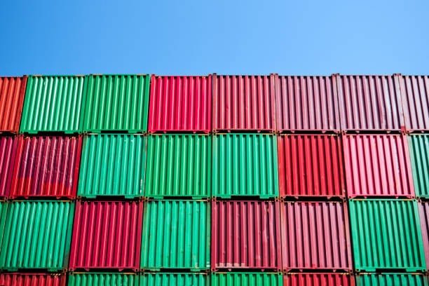 Wall of green and grey cargo containers arranged for export