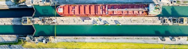 Overhead view of container ship passing through canal, representing the Suez route to Tunisia