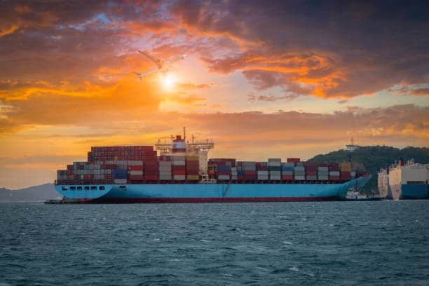 Large container ship departing at sunset, representing ocean freight to the UAE.