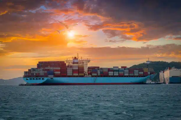 Large container ship departing at sunset, representing ocean freight to the UAE.