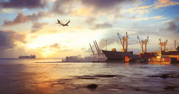 Airplane above a port at sunset, representing international shipping from China to Belgium.
