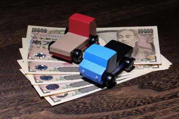 Two toy trucks on Japanese yen notes symbolizing international freight costs