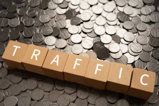 Word traffic on wooden blocks placed on coins symbolizing time and cost impact