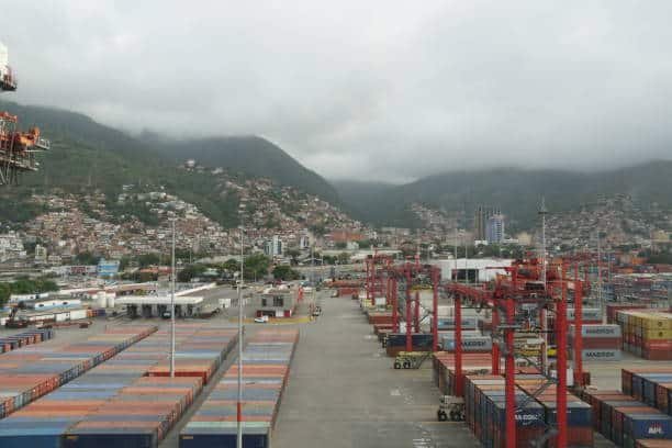 Shipping containers at UAE terminal yard with mountainous backdrop, receiving imports from China.