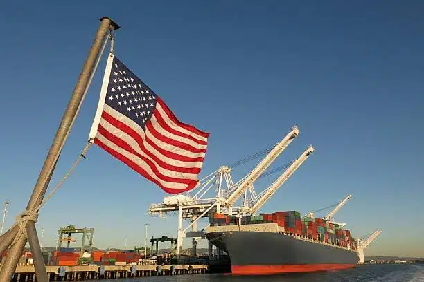 Container ship at U.S. port with American flag and cranes handling cargo operations