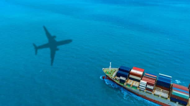 Aerial view of cargo ship with airplane shadow above, depicting air-sea logistics to Mexico.