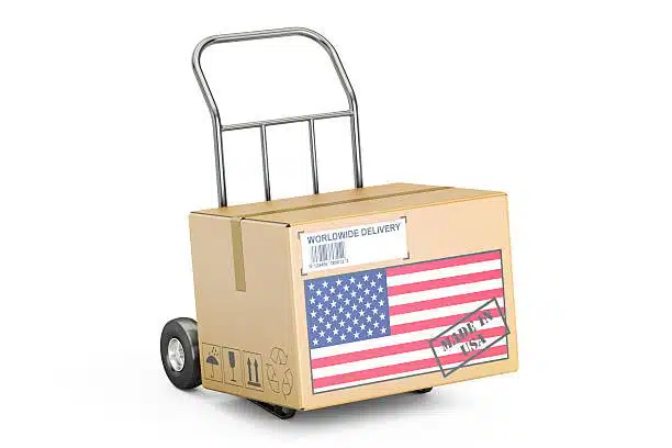 Cardboard parcel on hand trolley with USA flag and worldwide delivery stamp