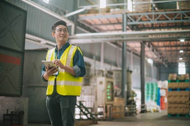 Logistics manager inspecting goods and shipment documentation in warehouse