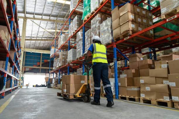 Worker managing inventory and pallets in a warehouse for shipment from China to Mauritania
