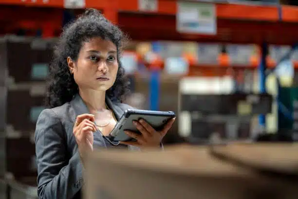 Female logistics manager checking warehouse inventory using a tablet