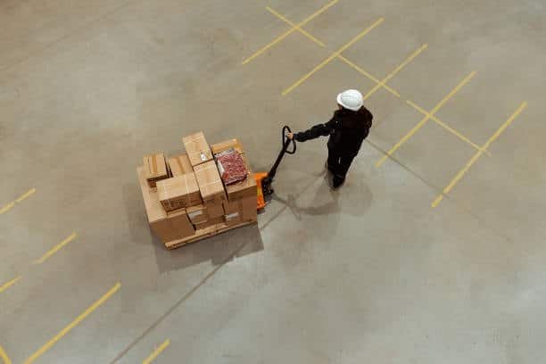 Warehouse staff pushing pallet jack with boxes prepared for shipping in dropshipping logistics