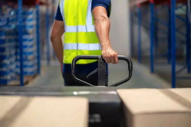 Logistics staff operating a pallet jack to move packages in the warehouse