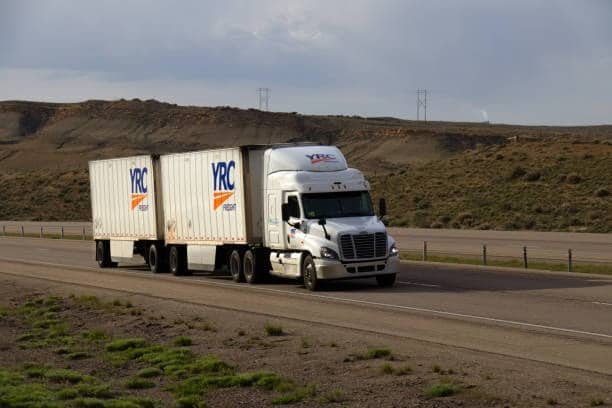 YRC branded LTL freight truck with dual trailers driving on an open highway
