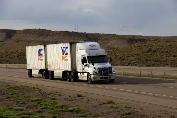 YRC branded LTL freight truck with dual trailers driving on an open highway