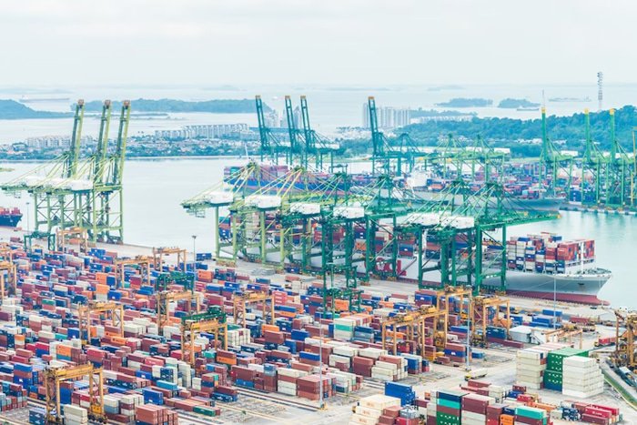 Wide aerial view of Singapore port filled with stacked containers and berthed ships