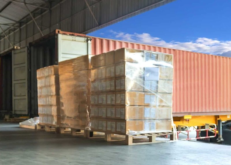 Palletized goods being loaded into a shipping container for transport from China to Malaysia