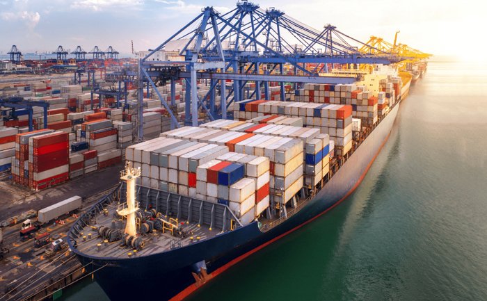 Massive container ship at port with hundreds of stacked TEUs and loading cranes