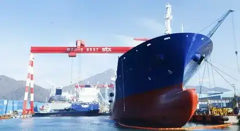 Large ocean-going cargo ship under construction at an Asian shipyard with cranes and dry dock